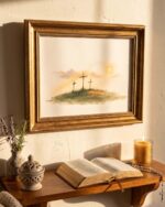 Three Crosses at Calvary print in an ornate gold frame above a wooden prayer shelf with an open Bible, lit candle, rosary and lavender in evening light