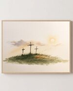 Three Crosses at Calvary fine art print in a light oak frame on a white wall, three crosses on a grassy hill at sunrise, Luke 23:33